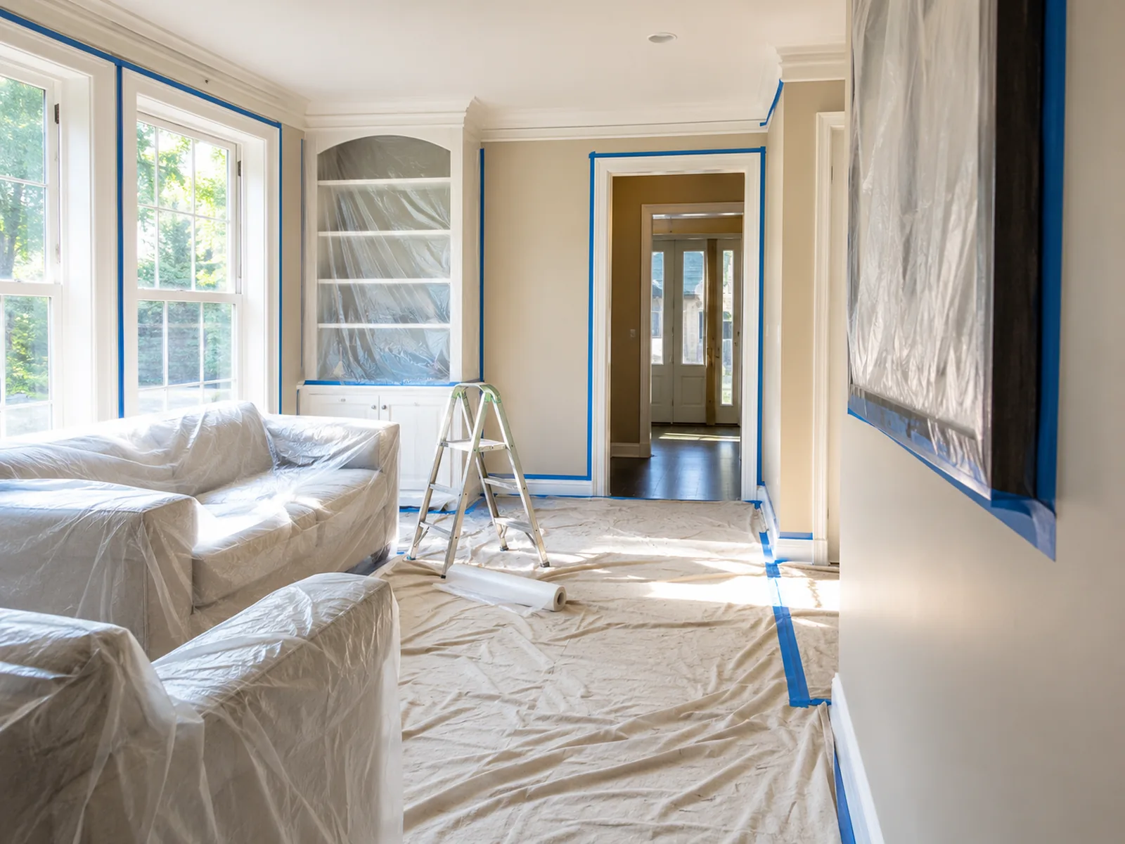 Living room furniture wrapped and floors protected before interior painting